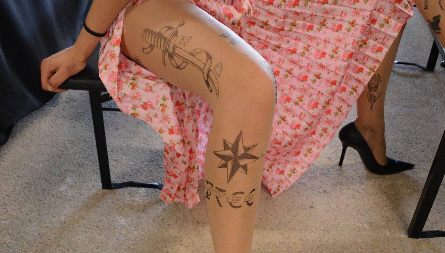 Худощавая красотка с татуировкой на ноге берет в рот резиновую игрушку и показывает прищепки на сосочках